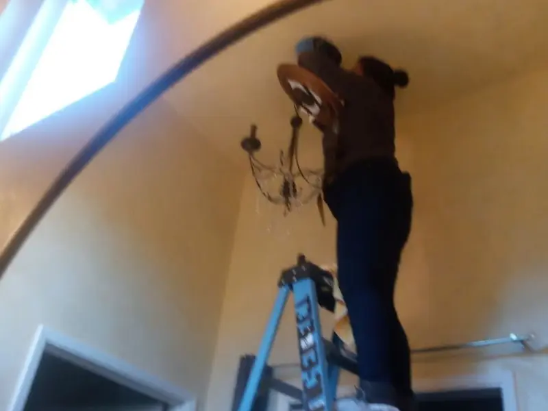 Electrician installing a chandelier in a Calexico residence